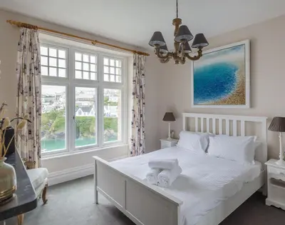 a bedroom with a white bed and a large window at Folly 2 in Port Isaac