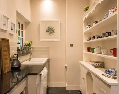 a white kitchen with a sink and a counter at Folly 2 in Port Isaac