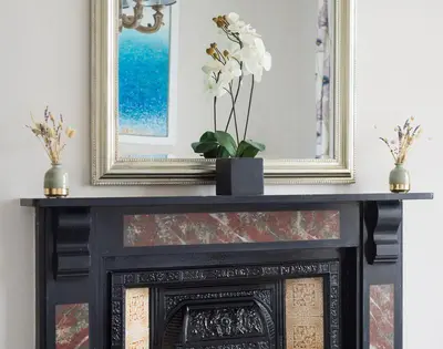 a fireplace with a black mantle with a vase of flowers at Folly 2 in Port Isaac