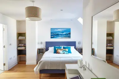 a bedroom with a blue bed and a mirror at Epphaven in Polzeath