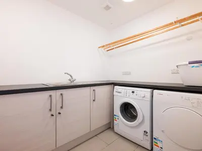 a white laundry room with a washer and dryer at Epphaven in Polzeath