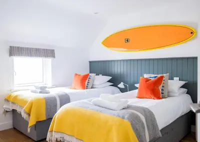 two beds in a room with a surfboard on the wall at Epphaven in Polzeath