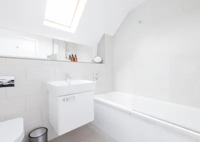 a white bathroom with a sink and a bath tub at Epphaven in Polzeath