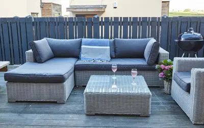 a patio with two couches and a table with wine glasses at Epphaven in Polzeath