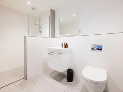 a white bathroom with a toilet and a sink at Epphaven in Polzeath