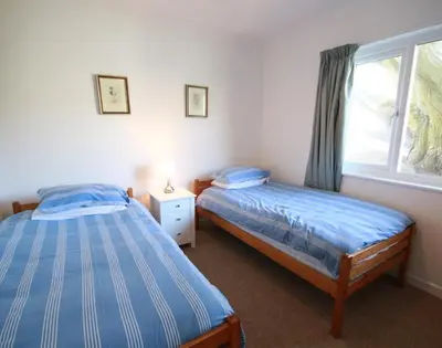 a bedroom with two twin beds and a window at Gullsway September Tide in Polzeath