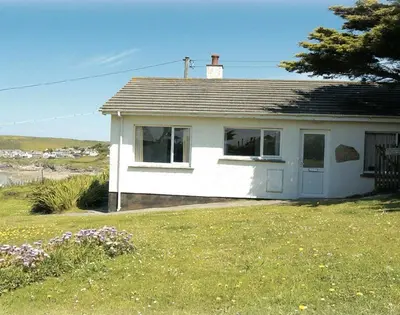 a small white house in a field with a yard at Gullsway September Tide in Polzeath