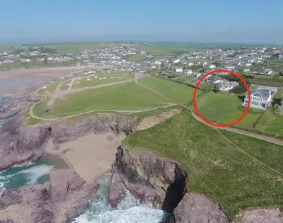 a house on a cliff next to a beach at Gullsway September Tide in Polzeath