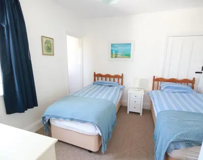 a bedroom with two beds with blue and white sheets at Gullsway Kittiwake in Polzeath