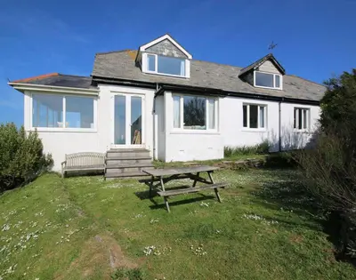 a white house with a picnic table in front of it at Gullsway Kittiwake in Polzeath