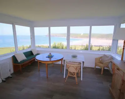 a living room with a table and chairs and windows at Gullsway Kittiwake in Polzeath