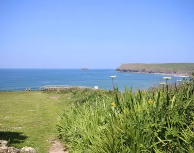 a field of grass with a view of the ocean at Gullsway Kittiwake in Polzeath