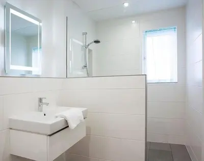 a white bathroom with a sink and a mirror at Kellan in Polzeath