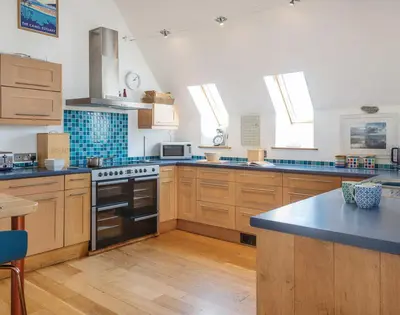 a kitchen with wooden cabinets and a stove top oven at Sandy Hills 8 in Padstow