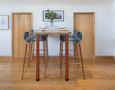 a table with four stools around it in a room at Sandy Hills 8 in Padstow