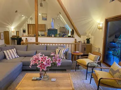 a living room with a couch and a table with flowers at Sandy Hills 8 in Padstow