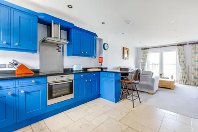 a kitchen with blue cabinets and a couch in the background at Rock Lobster in Port Isaac