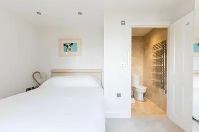 a white bedroom with a bed and a toilet at Rock Lobster in Port Isaac