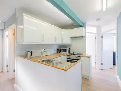 a kitchen with white cabinets and a sink at Pinewood Flat 5 in Polzeath