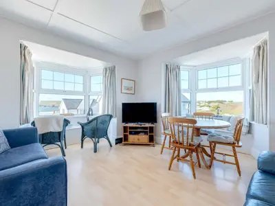 a living room with a blue couch and a table and chairs at Pinewood Flat 5 in Polzeath