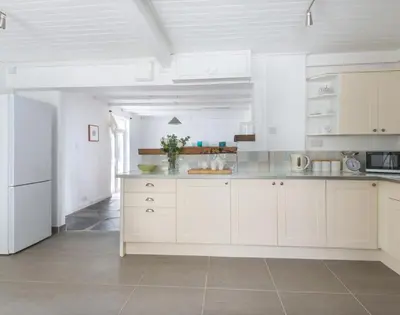 a large white kitchen with white cabinets and appliances at Signal Post in Port Isaac