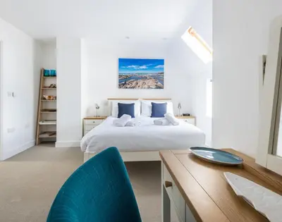 a bedroom with a bed and a desk with a blue chair at Rainer Rocks in Polzeath