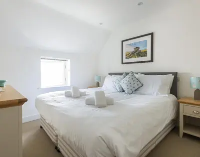 a bedroom with a large white bed with white pillows at Rainer Rocks in Polzeath