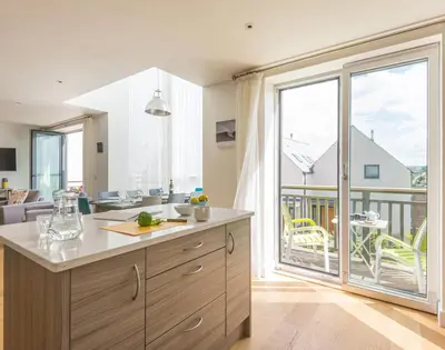 a kitchen with a large sliding glass door leading to a balcony at Rainer Rocks in Polzeath