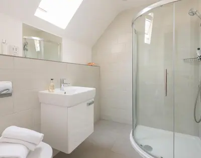a white bathroom with a sink and a shower at Rainer Rocks in Polzeath