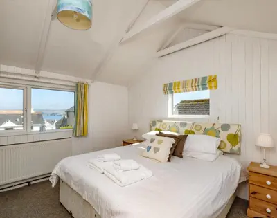 a bedroom with a large white bed and a window at The Folly in Port Isaac