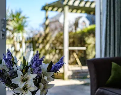 a vase of purple and white flowers next to a couch at The Folly in Port Isaac
