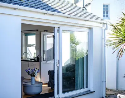 an open sliding glass door of a white house at The Folly in Port Isaac