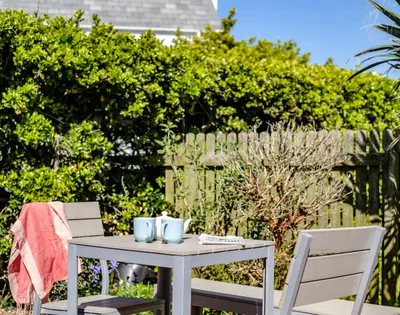 a table with two chairs and a table with mugs on it at The Folly in Port Isaac