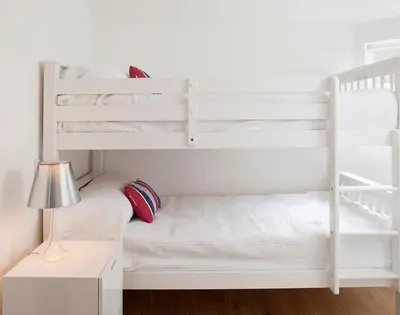 a white bunk bed with a desk and a lamp at The Beach Hut in Polzeath