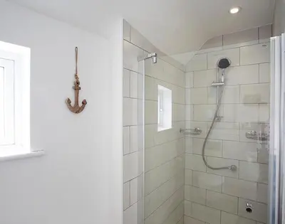 a bathroom with a shower with a glass door at The Beach Hut in Polzeath