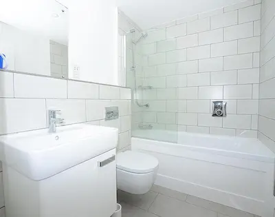 a white bathroom with a sink and a toilet and a tub at The Beach Hut in Polzeath