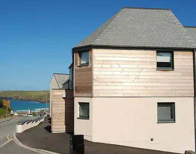 a building next to a road next to the ocean at The Beach Hut in Polzeath