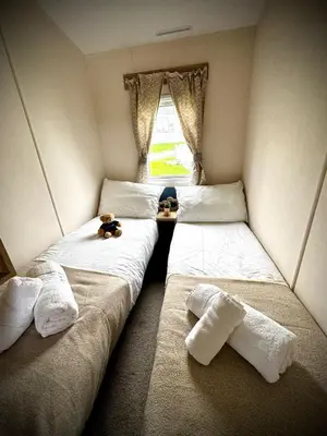 two twin beds in a room with a window at PV70 newquay bay resort in Porth