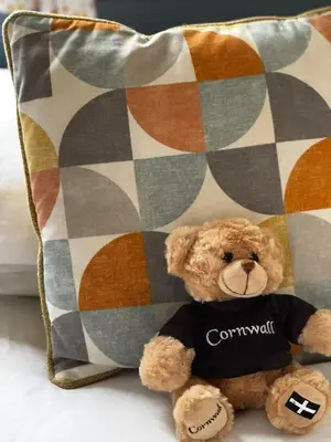 a brown teddy bear sitting next to a pillow at PV70 newquay bay resort in Porth