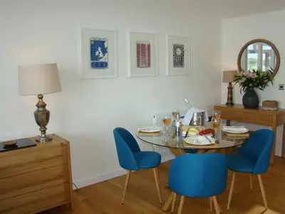 a dining room with a glass table and blue chairs at Topsail - Falmouth in Falmouth