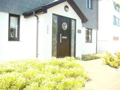 a black door on a white house with bushes at Topsail - Falmouth in Falmouth
