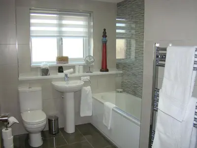 a bathroom with a toilet and a sink and a tub at Topsail - Falmouth in Falmouth