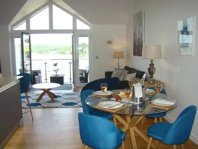 a living room with a glass table and blue chairs at Topsail - Falmouth in Falmouth