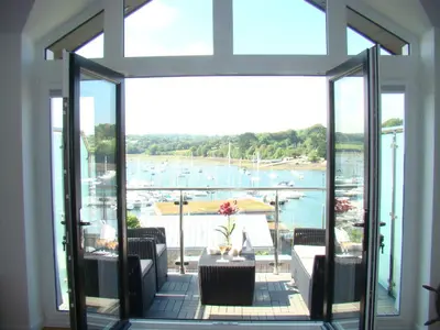 a room with a balcony with a view of a marina at Topsail - Falmouth in Falmouth