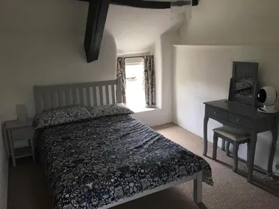a bedroom with a bed and a desk and a window at Picture perfect cottage in rural Tintagel in Tintagel