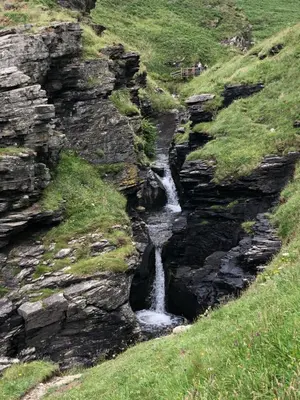 a waterfall on the side of a rocky hill at Picture perfect cottage in rural Tintagel in Tintagel