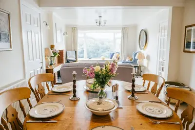 a dining room table with a vase of flowers on it at Finest Retreats - Tideway in Saint Clement