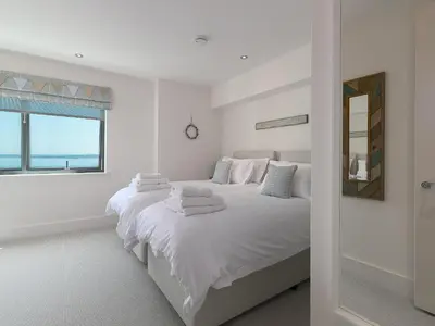 a white bedroom with a bed with towels on it at Crystal Bay in St Ives
