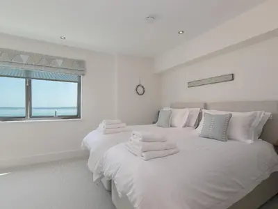 a white bedroom with two beds with towels on them at Crystal Bay in St Ives