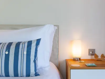 a bed with a pillow and a lamp on a table at Crystal Bay in St Ives